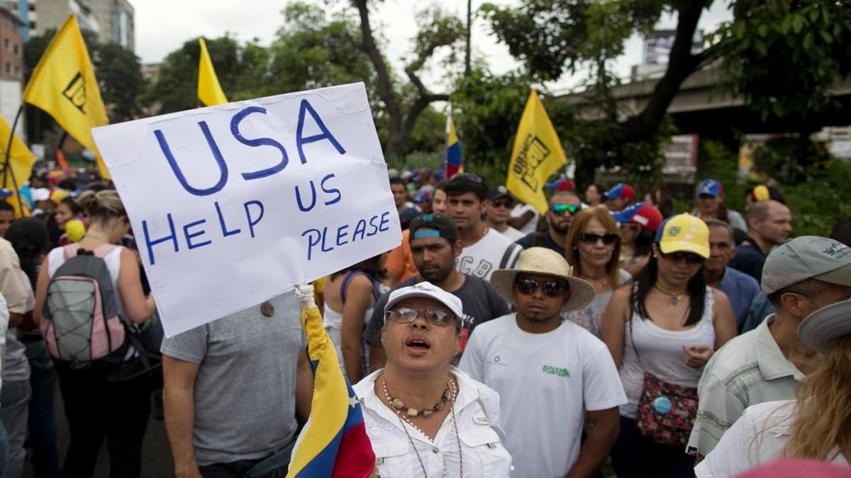 A woman holds up a sign asking for help from the United States during a protest against Venezuela's President Nicolas Maduro in Caracas, Venezuela, Wednesday, Oct. 26, 2016.