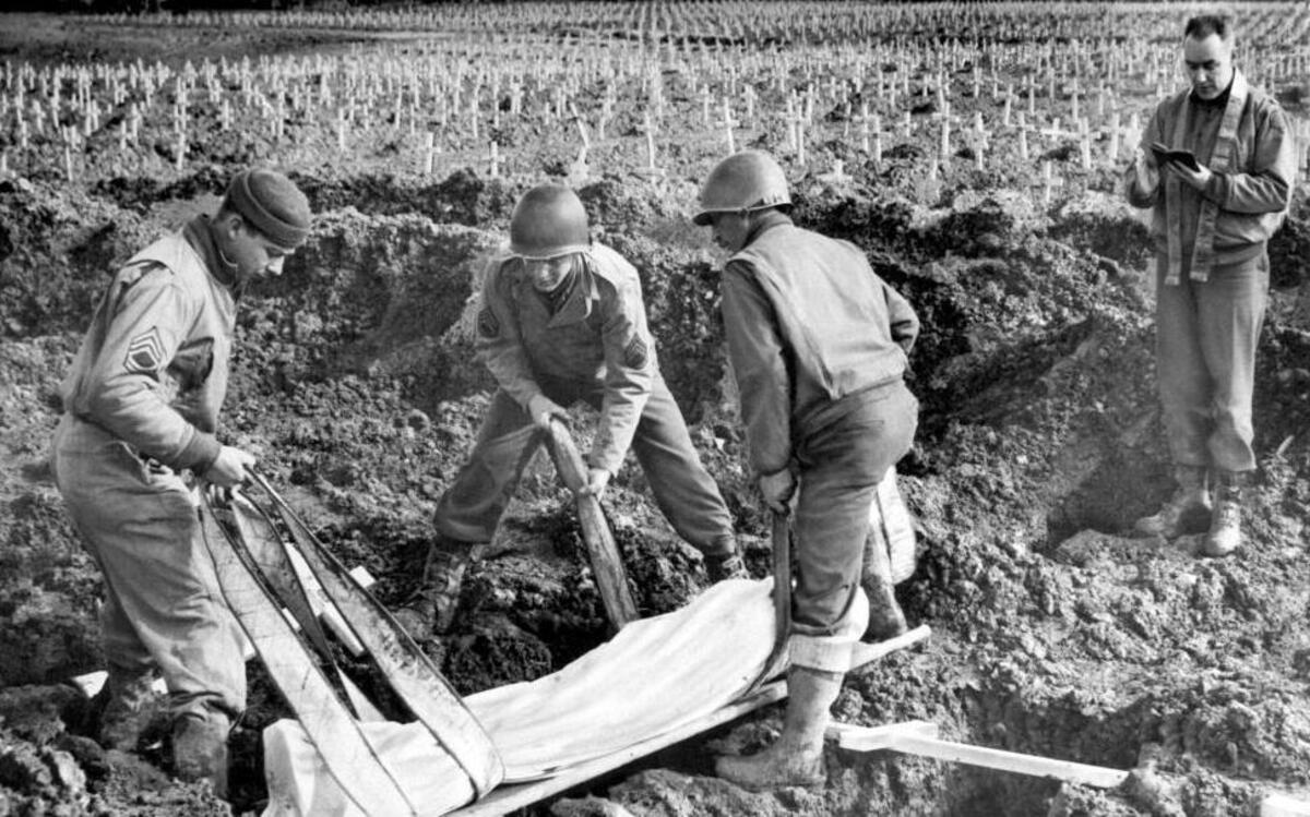 Maj. John B. Day, right, an Army chaplain from Springfield, Ill., conducts burial services for an unidentified American soldier in the largest military cemetery on the western front at Henri Chappell in Belgium in an undated photo. Lowering the body into the grave are T/Sgt. A.H. Herberts, of Chester, Ill; S/Sgt. Vito Mastrangelo,of Visalia, Calif.; and Pfc. Irvin W. Kestner, of Oakland, Calif., left to right. Crosses in the background marked the graves of several thousand other American dead. Undated photo.