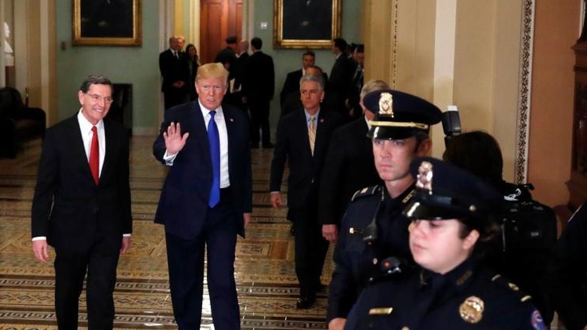 President Donald Trump, center, walks with Sen. John Barrasso, R-Wyo., left, as he arrives at the Capitol to meet with GOP lawmakers about moving his agenda and passing the Republican tax bill, in Washington, Tuesday, Nov. 28, 2017.