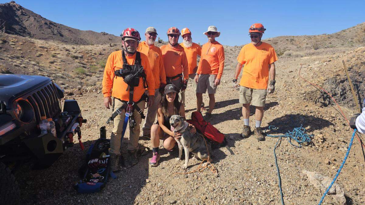 The woman and her dog are pictured with rescuers.