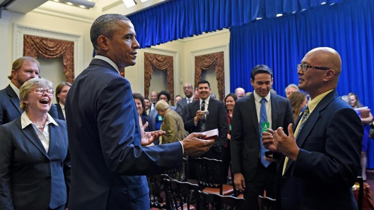 
President Barack Obama holds a coin given to him by Hawaii State Senator Will Espero, right, as he meets with state legislators in the Eisenhower Executive Office Building in part of the White House complex in Washington, Wednesday, Sept. 30, 2015.
