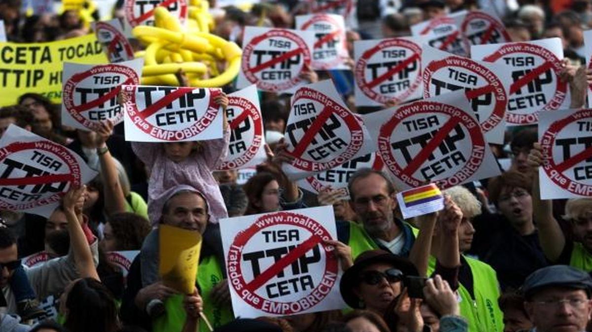 People holding up posters against the proposed Trans-Atlantic Trade and Investment Partnership march during a protest in Madrid, Saturday, Oct. 15, 2016. Several hundred people have gathered in Madrid to protest the major free trade deal between the United States and the European Union.