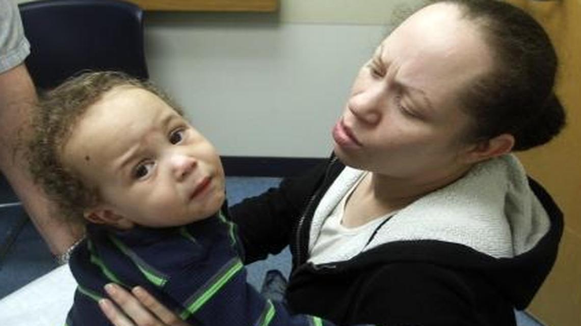 In this Feb. 23, 2012, photo, family nurse practitioner Terrance James, left, examines Kamiyan Cooper, 1, as his mother Kesha Wilson holds him at the Multnomah County's Mid County Health Center, in Portland, Ore. Hoping to solidify waning support for the GOP bill to replace Obamacare, House Republicans amended it this week to allow states to require healthy adults, including parents, to work for their Medicaid health coverage.