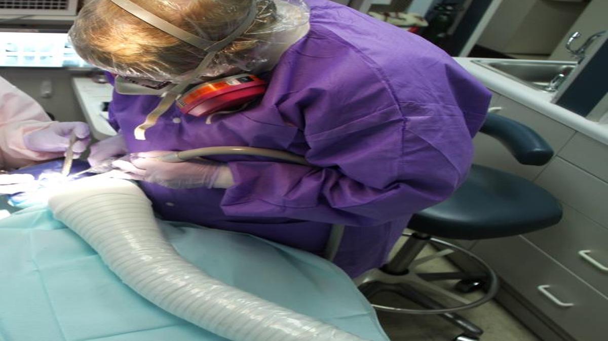 Scranton, Pa., mercury-free dentist Dr. Blanche Grube and her assistant remove a mercury/"silver filling" from a patient. All three are draped and covered for protection from mercury vapor and particles.