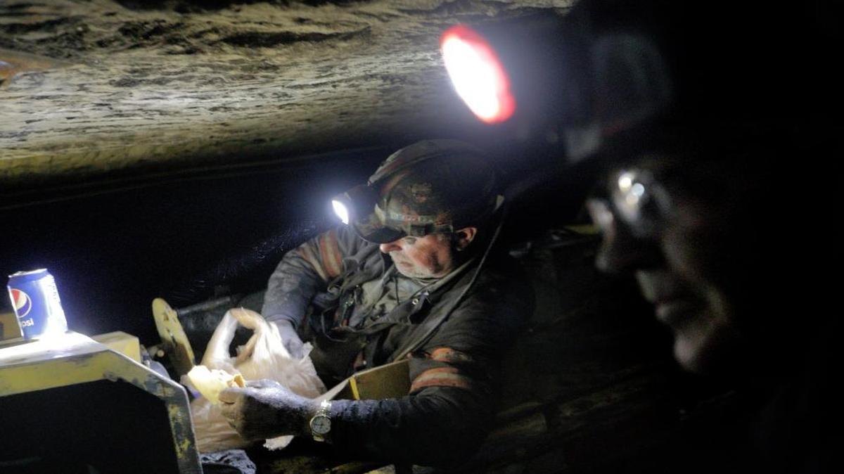 Scott Tiller, a coal miner of 32 years, eats his lunch while laying down on a man trip, a cart that shuttles miners underground, as he works a shift in a mine less than 40-inches high in Welch, W.Va., on May 11, 2016.