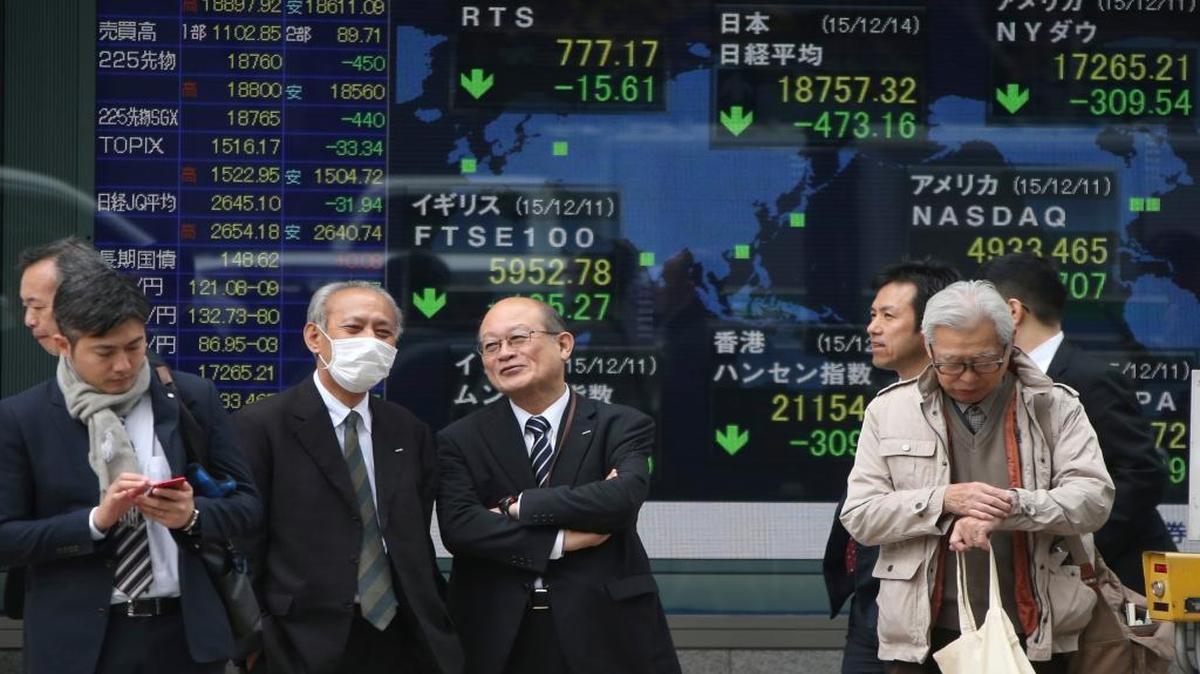 People stand in front of an electronic stock board in Tokyo on Dec. 14, 2015. Investors globally await the U.S. Federal Reserve’s decision this week on its first interest-rate hike in a decade.