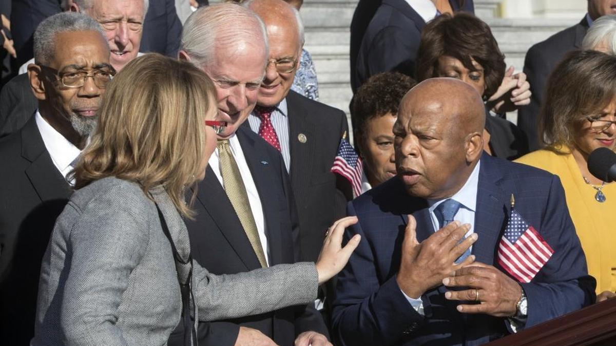 Former Rep. Gabby Giffords, D-Ariz., who survived an assassination attempt in 2011, left, reaches out to civil rights leader Rep. John Lewis, D-Ga., right, as House Democrats call for action on gun safety legislation after the deadly mass shooting in Las Vegas, at the Capitol in Washington, Wednesday, Oct. 4, 2017.