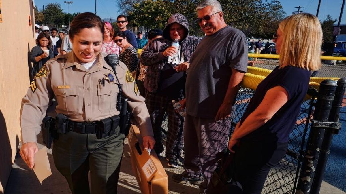 Voters who had waited hours in line to vote watch as a Los Angeles County sheriff's deputy arrives with ballot marking devices in the Van Nuys section of Los Angeles on Tuesday, Nov. 8, 2016. Frustrations ran high at the Los Angeles polling place as voters were left waiting when ballot marking devices arrived late.