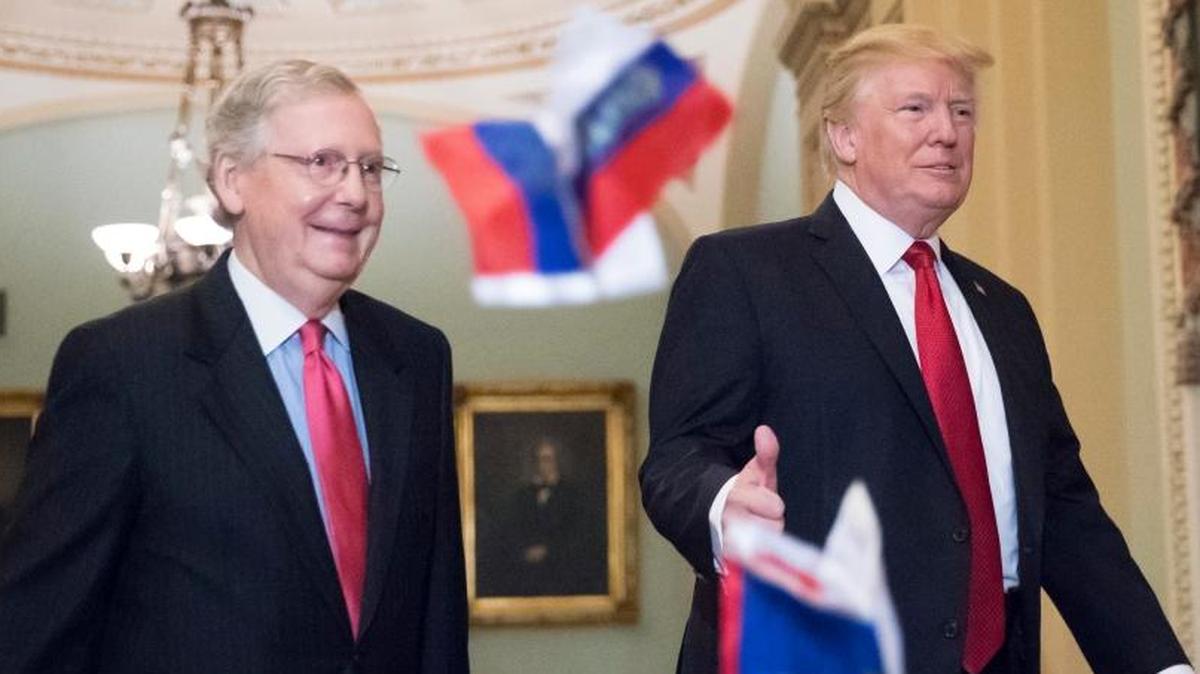 Small Russian flags bearing the word "Trump" are thrown by a protester toward President Donald Trump, as he walks with Senate Majority Leader Mitch McConnell, R-Ky., on Capitol Hill to have lunch with Senate Republicans.
