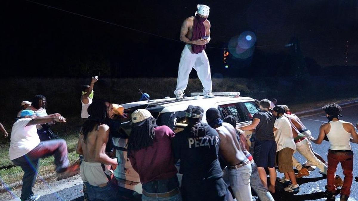 Protesters surround a police vehicle on Old Concord Road in Charlotte, N.C., on Tuesday night. A protest began on Old Concord Road at Bonnie Lane, where a Charlotte-Mecklenburg police officer had fatally shot a man in the parking lot of The Village at College Downs apartment complex Tuesday afternoon. The man who died was identified late Tuesday as Keith Scott, 43, and the officer who fired the fatal shot was CMPD Officer Brentley Vinson.