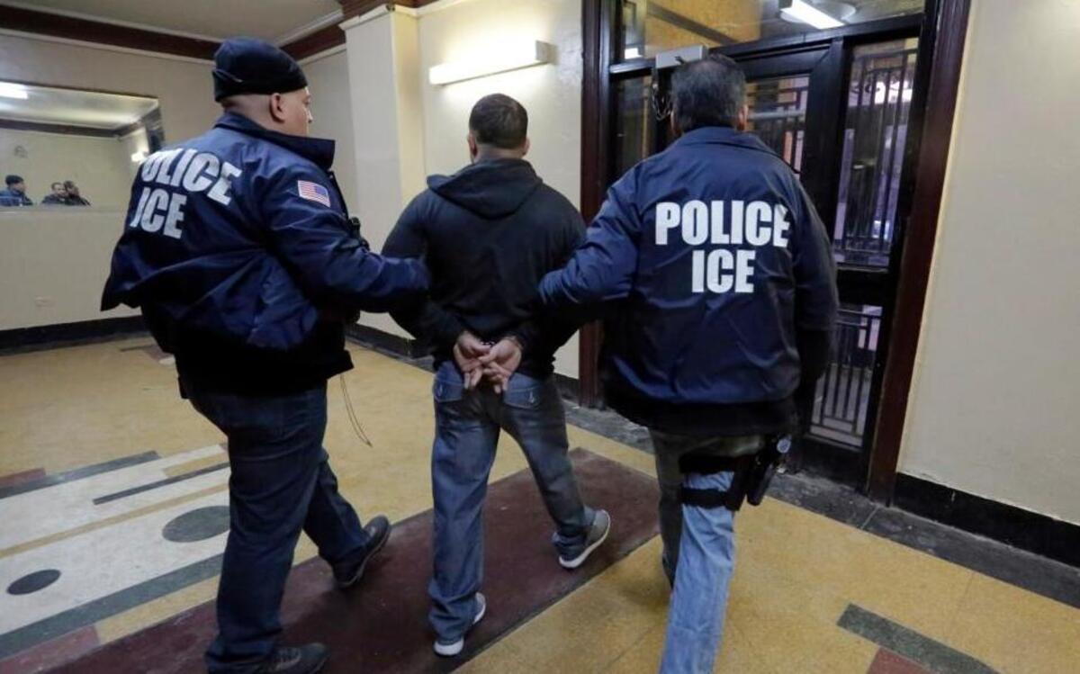 In this March 3, 2015, photo, Immigration and Customs Enforcement officers escort an arrestee in an apartment building, in the Bronx borough of New York, during a series of early-morning raids. (AP Photo/Richard Drew)