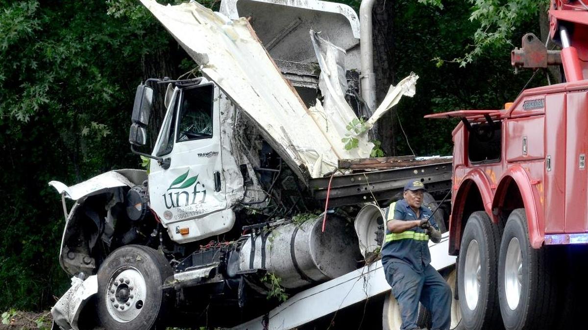 A worker loads a severely damaged semi cab onto the flatbed of his truck, after an eight-vehicle wreck in South Carolina that started after a tractor trailer on Interstate 95 hydroplaned and hit a tree, causing the tree to fall into the roadway.