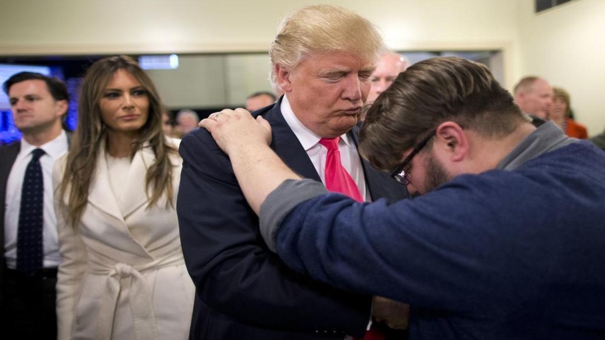 Pastor Joshua Nink, right, prays for Republican presidential candidate Donald Trump, as his wife, Melania, left, watches after a Sunday service at First Christian Church, in Council Bluffs, Iowa. Trump has vowed to “totally destroy” a 1950s law preventing churches from endorsing or opposing political candidates.