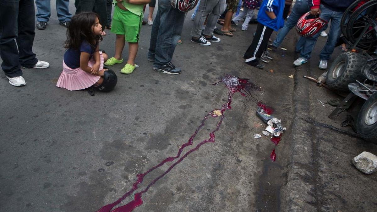 In this Dec. 1, 2014, photo, a girl closes her eyes as she sits at the scene of a murder in Tegucigalpa, Honduras. DHS Secretary Jeh Johson said deportations to Central America would continue for those caught attempting the border illegally after exhausting their appeals.