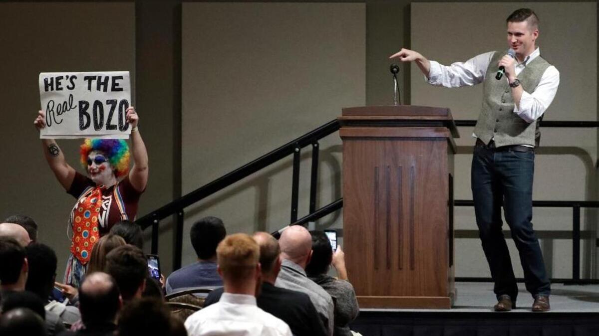 Richard Spencer, who leads a movement that mixes racism, white nationalism and populism, points to demonstrator carrying a sign as he speaks at the Texas A&M University campus Tuesday, Dec. 6, 2016, in College Station, Texas. Texas A&M officials say they didn’t schedule the speech by Spencer, who was invited to speak by a former student who reserved campus space available to the public.