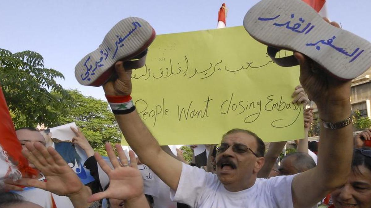 
Hundreds of thousands of Syrians protest in front the U.S. embassy in Damascus against the visit of the U.S. Ambassador to Syria, Robert Ford, who visited the city of Hama, Syria, on July 7, 2011. The Arabic words on the shoes read: "The dirty ambassador," right, and "the U.S. ambassador," left.
