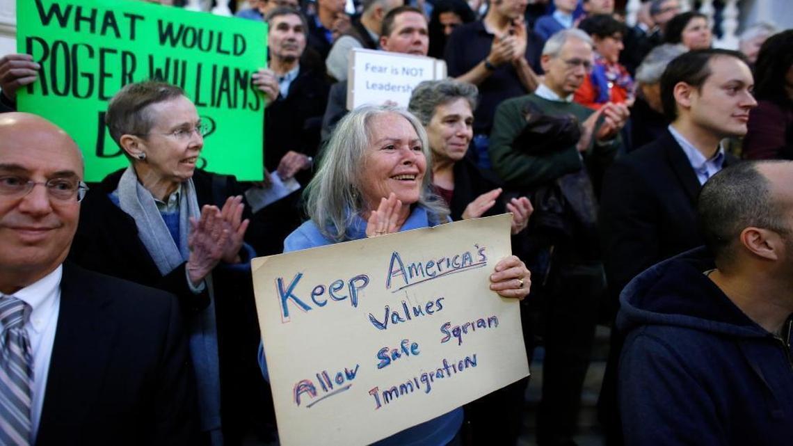 Linda Kushner, of Providence, R.I., center, displays a placard during a rally Thursday, Nov. 19, 2015, at the statehouse in Providence, demanding that Syrian refugees be allowed to enter Rhode Island and the United States following the terror attacks in Paris. (AP Photo/Steven Senne)