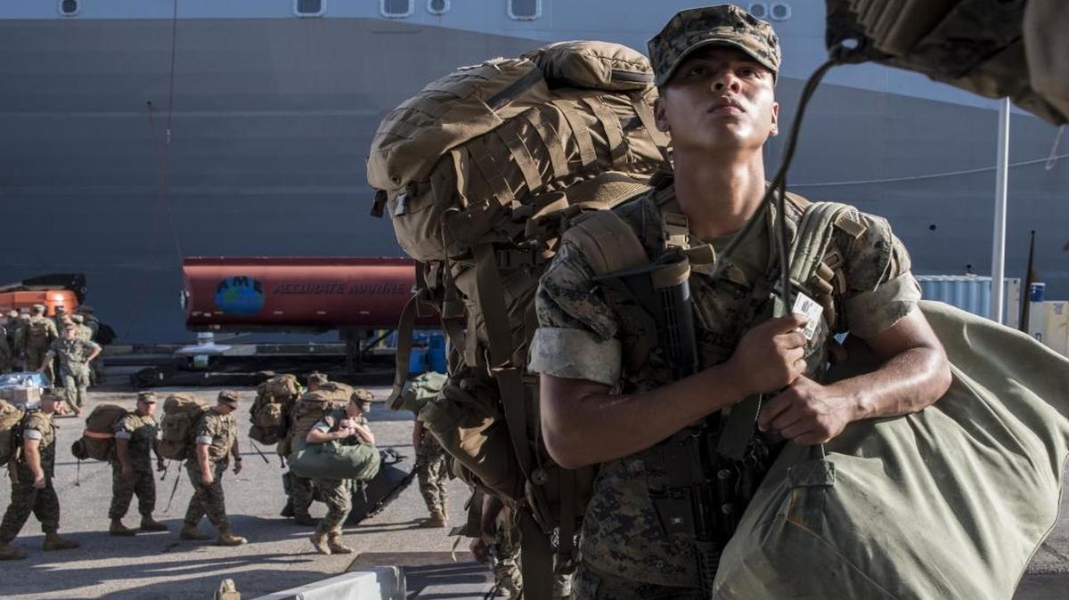 Marines assigned to the 26th Marine Expeditionary Unit embark the amphibious assault ship USS Kearsarge in Norfolk, Va., in August. The Defense Department has some 100,000 employees on temporary clearances awaiting full security reviews.