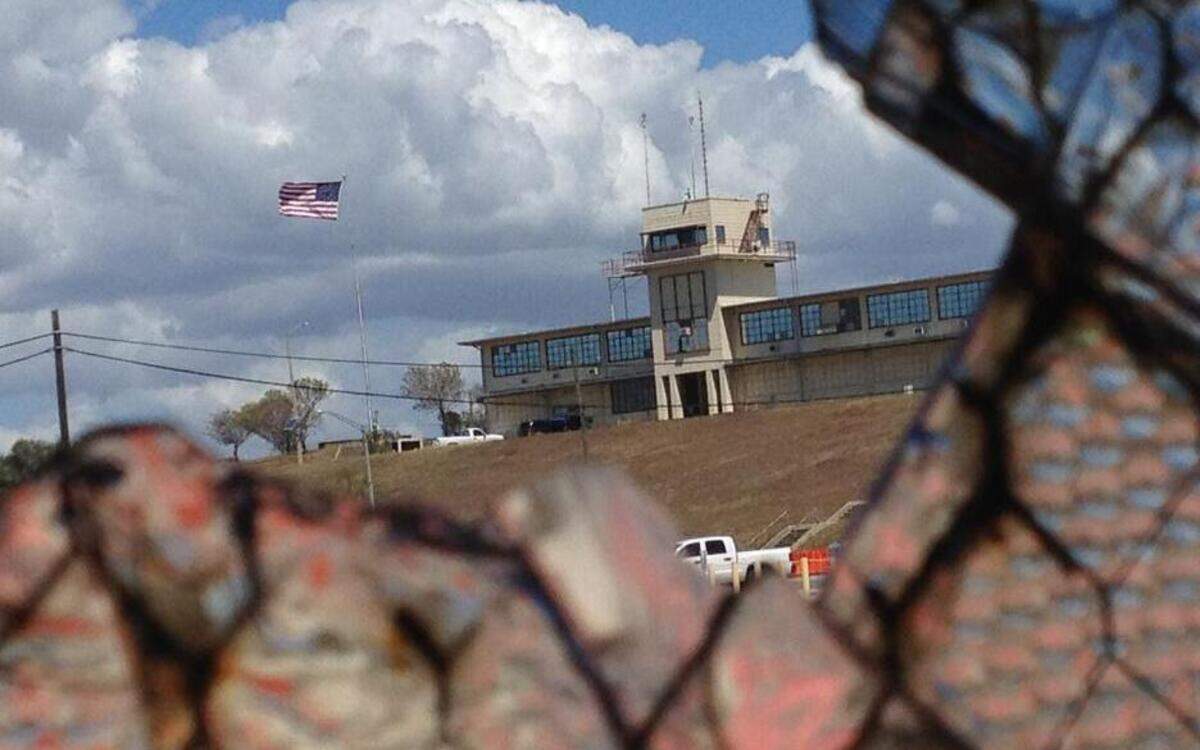 The flag flying over a portion of the war court complex, Camp Justice, as seen through a broken abandoned air hangar window at the U.S. Navy base at Guantánamo Bay, Cuba, on Feb. 28, 2015, in an image approved for release by the U.S. military.