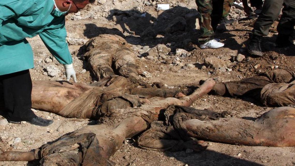 
In this photo taken on June 12, 2011 during a government-organized tour for media, a Syrian security officer shows dead bodies, some still in uniform, that were beheaded or struck on the head with an axe, near the city's Military Police building, in the town of Jisr al-Shughour, north of Damascus, Syria. Syrians poured across the border to refugee camps in Turkey, fleeing a military crackdown that sent elite forces backed by helicopters and tanks into the northern town.
