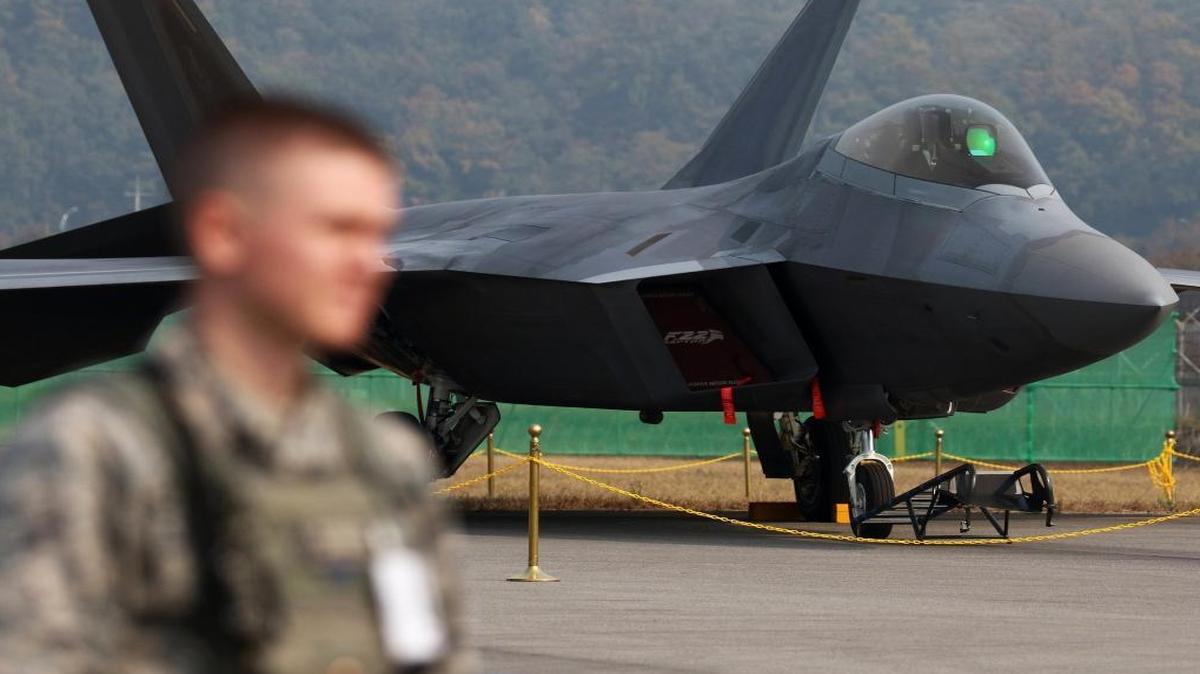A member of the U.S. Air Force stands in front of an F-22 Raptor at Seoul Airport in South Korea, on Oct. 19, 2015. The Air Force says it faces an imminent shortfall of 700 pilots by the end of 2016.