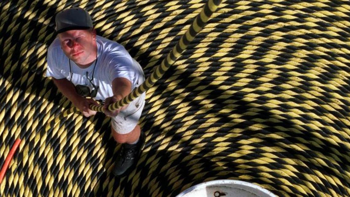 A crewman pulls on undersea cable that will be laid in the Caribbean in this 2001 photo from the Port of Miami. The crewman stands in a cable well holding 120 miles of cable.