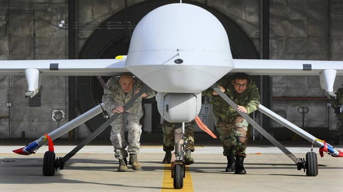 A ground crew from U.S. Air Force 163rd Reconnaissance Wing of the California National Guard push a Predator aircraft from its hanger at George Air Base in Victorville, Calif.