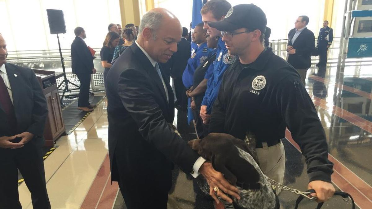 Homeland Security Secretary Jeh Johnson pets a trained dog on Wednesday, Sept. 7, 2016, at Ronald Reagan Washington National Airport, where the dog works with a Transportation Security Administration officer at a passenger checkpoint.