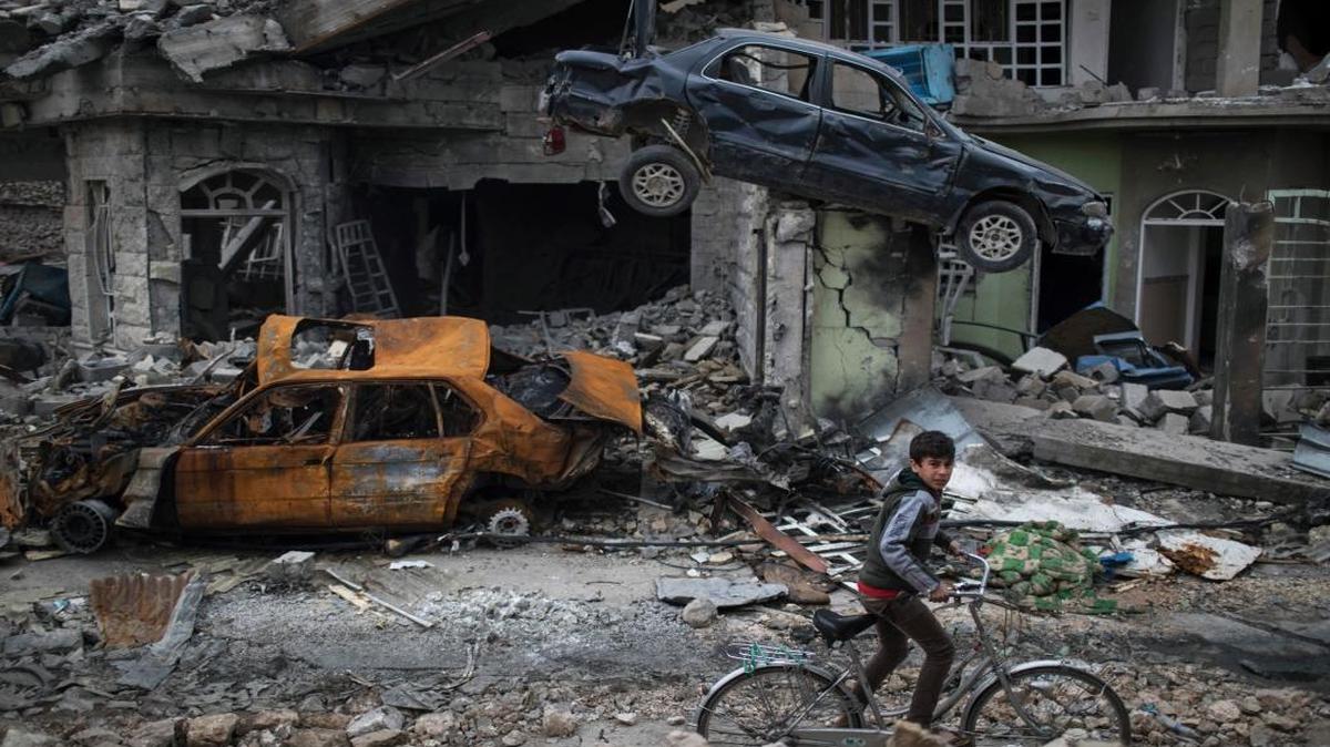A boy rides his bike past destroyed cars and houses in a neighborhood recently liberated by Iraqi security forces, on the western side of Mosul, Iraq. The battle for western Mosul, including the narrow alleyways of the old city, looks to be the most devastating yet for Iraqi civilians trapped between advancing troops and increasingly desperate Islamic State militants.