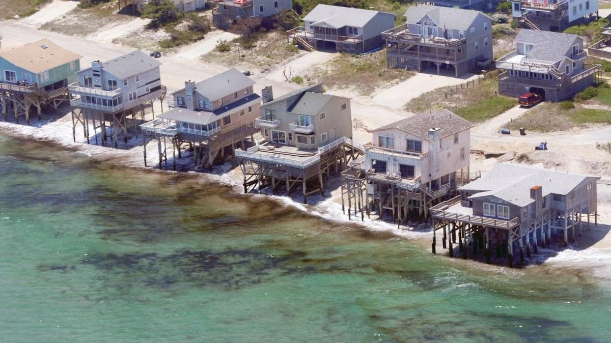 Hurricane Irene hammered the Outer Banks of North Carolina in August of 2011, eroding beaches and leaving several waterfront homes, including these in Nags Head, exposed to the waves. Authorities later condemned these homes, and they have since been removed. Scientists say sea-level rise is accelerating in North Carolina and other Southeastern states, putting thousands of waterfront homes at risk.