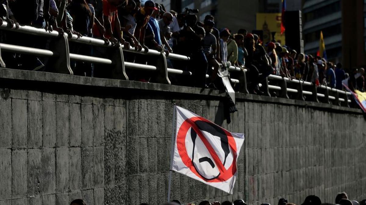 A demonstrator waves a flag Monday in Caracas with the the crossed out image of Venezuelan President Nicolás Maduro during a tribute to those killed during protests against the government.