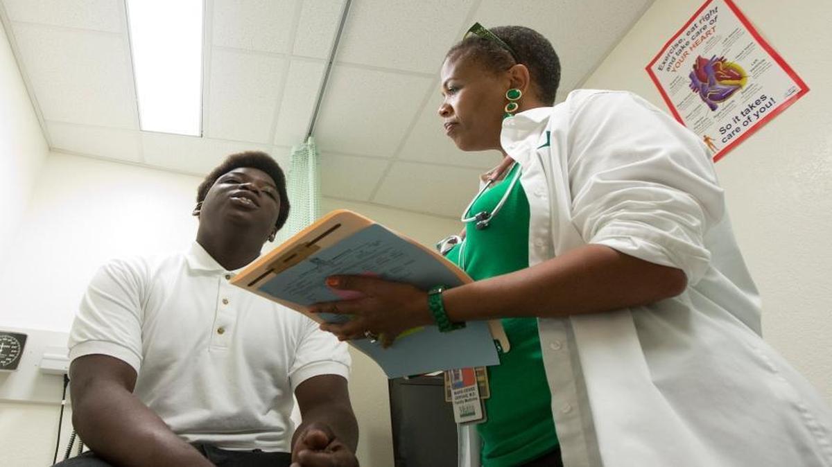 Dr. Marie-Denise Gervais talks to Amos LeClerc as she examines him at a clinic in a Miami high school, Aug. 19, 2014.