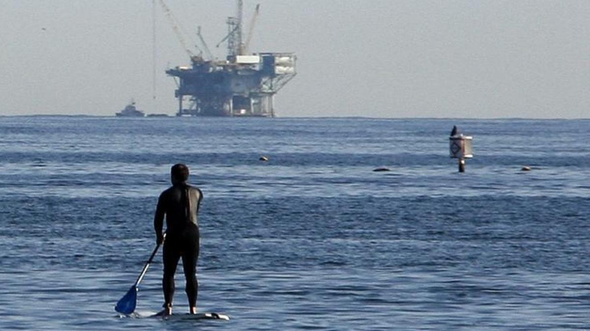 President Trump’s plan to expand offshore oil drilling has alarmed many on the West Coast, including California, which already has oil rigs off its shoreline and a history of spills that have harmed tourism and the environment. Here a man paddles out on a surfboard from the beach, with an oil platform in the background, in Santa Barbara on Jan. 28, 2009.