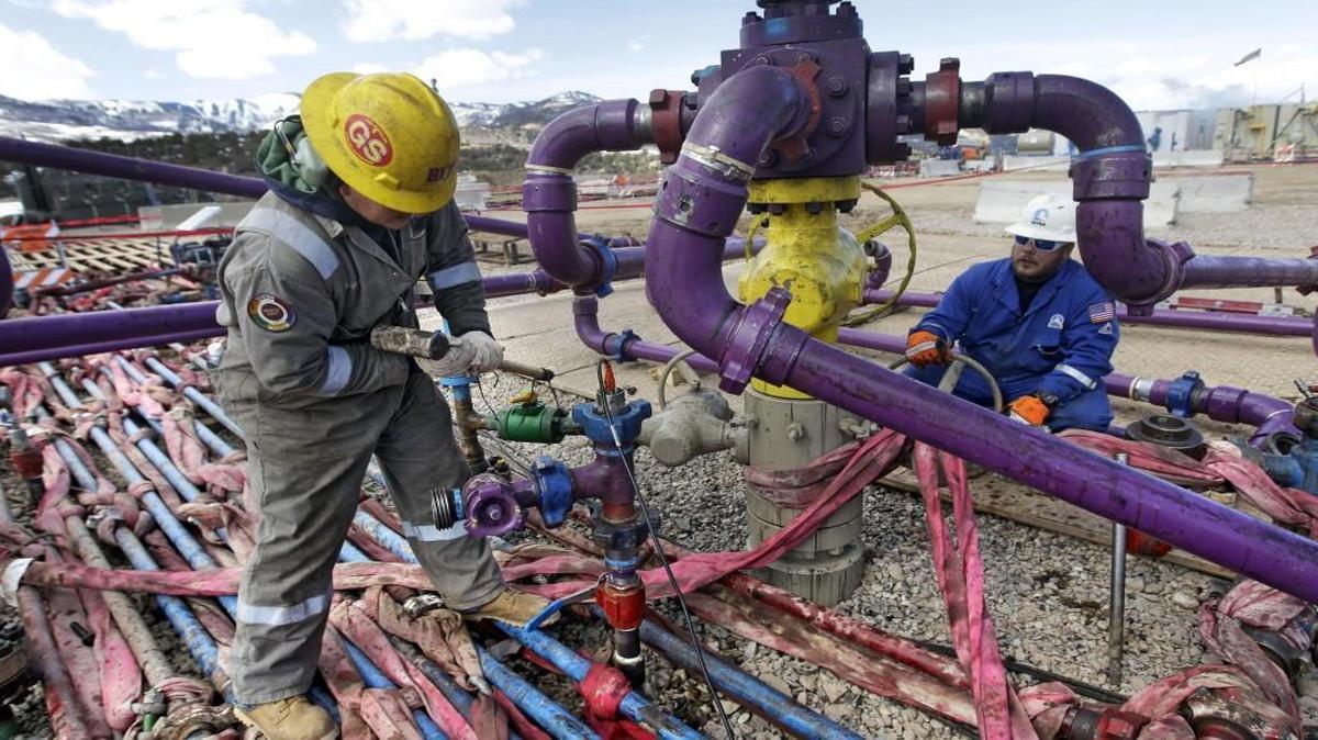 Workers tend to a well head during a hydraulic fracturing operation at an Encana Oil & Gas (USA) gas well outside Rifle, in western Colorado.