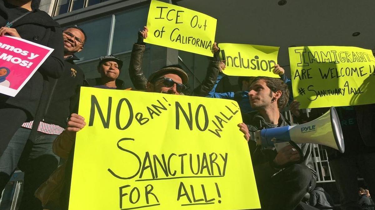 Protesters hold up signs outside a courthouse where a federal judge will hear arguments in the first lawsuit challenging President Donald Trump's executive order to withhold funding from communities that limit cooperation with immigration authorities Friday, April 14, 2017, in San Francisco.