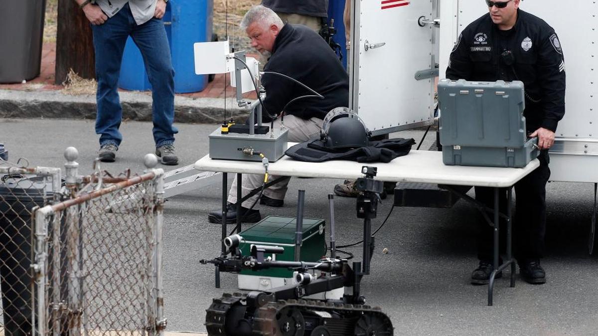 A member of the Cambridge police bomb squad, right, deploys a robot on Norfolk Street during a search for searching a suspect in the Boston Marathon bombings in Cambridge, Mass., Friday, April 19, 2013.