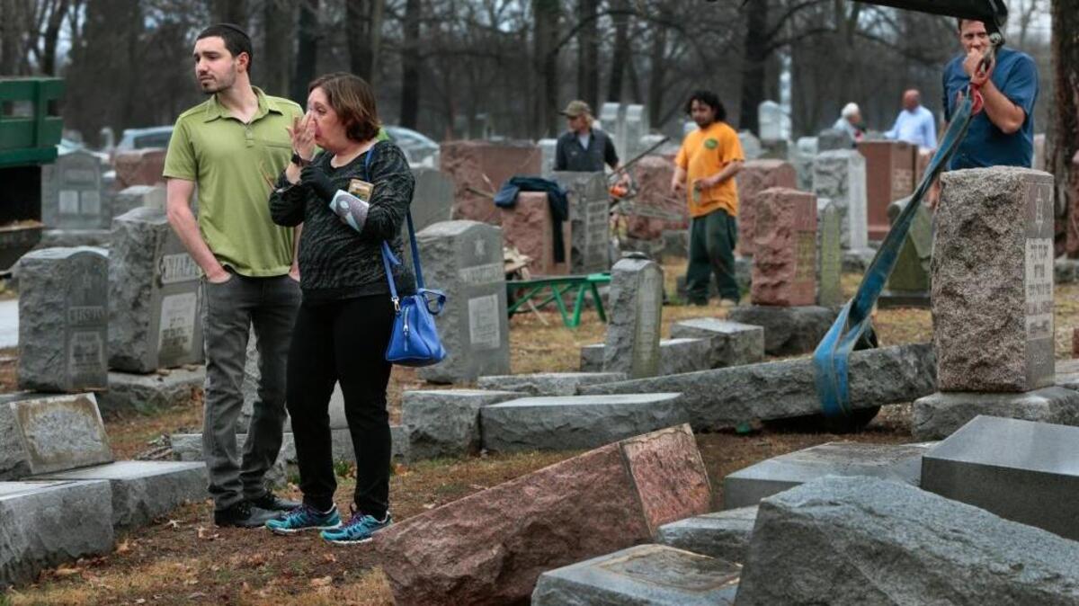 Sally Amon and her son Max Amon of Olivette, Mo., react as they saw toppled gravestone of her grandmother Anna Ida Hutkin at Chesed Shel Emeth Cemetery in University City, a suburb of St. Louis on Tuesday, Feb. 21, 2017. Vandals have damaged or tipped over 154 headstones at the Jewish cemetery in suburban St. Louis, leaving the region's Jewish community shaken and anxious.
