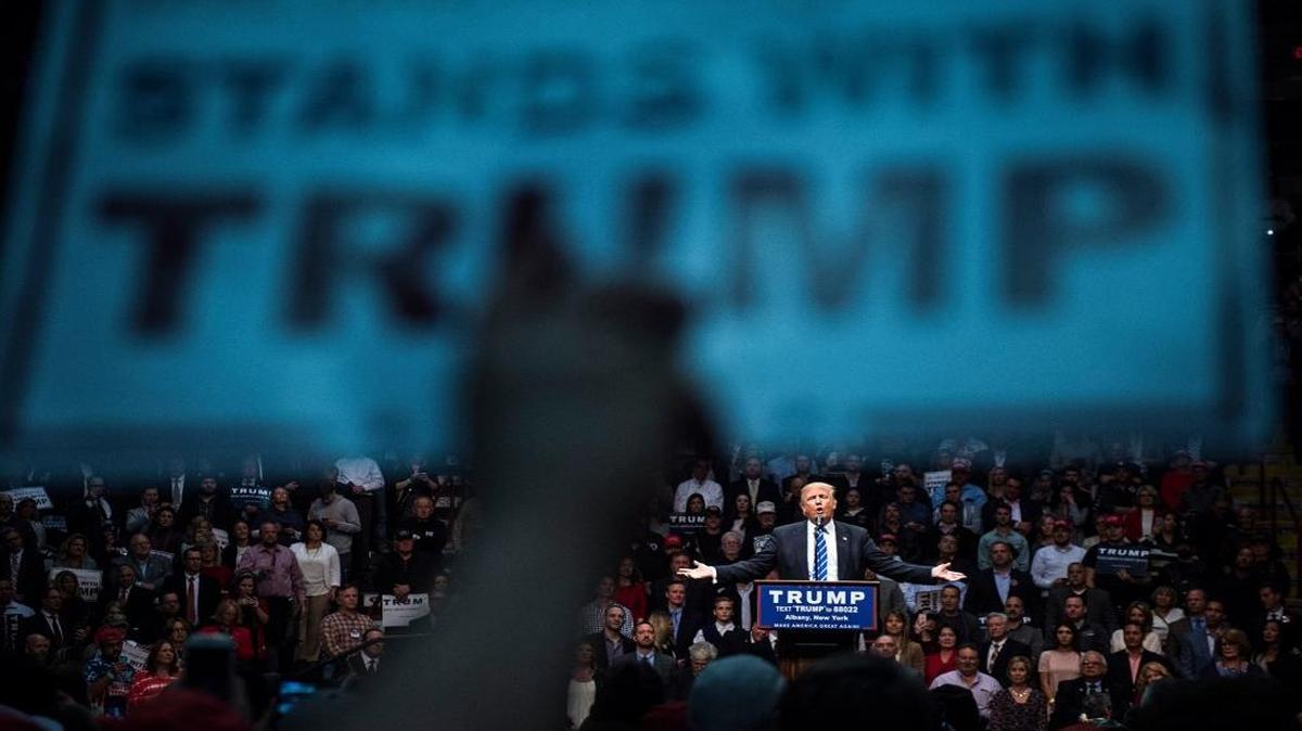 A supporter holds up a sign as Republican presidential candidate Donald Trump speaks during a campaign event at the Times Union Center in Albany, New York, on Monday.