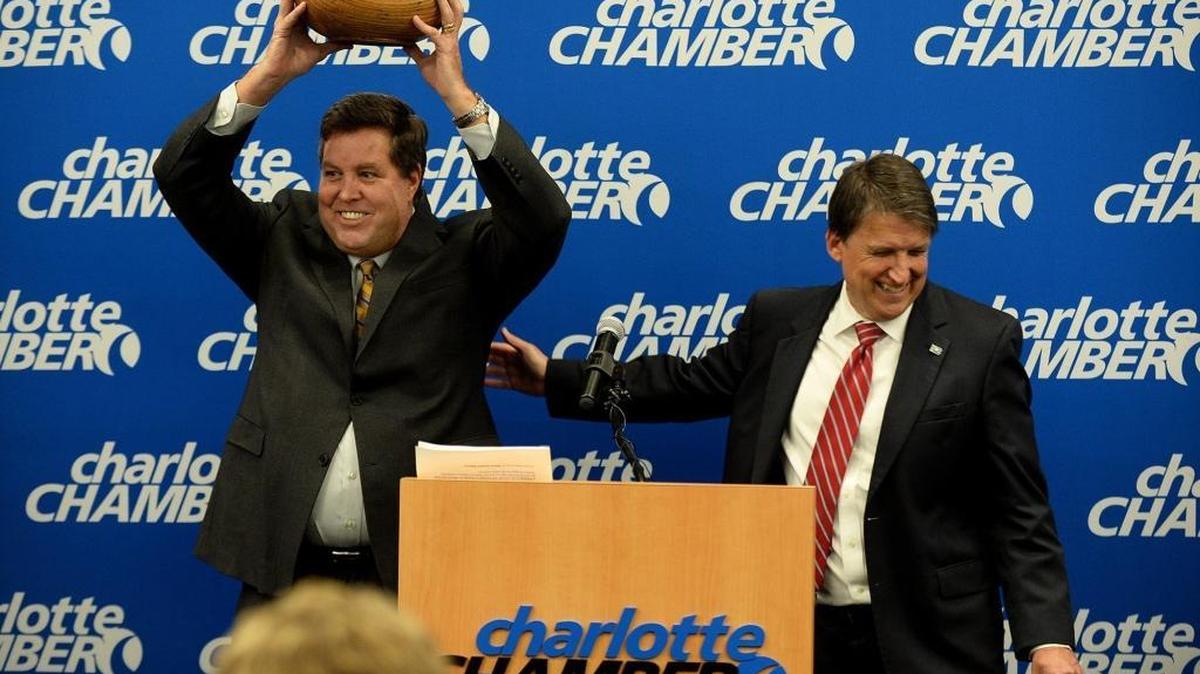 John McCabe, left, senior vice-president of Global Operations at PayPal, holds up a carved wooden bowl (made by an artist from a tree struck by lightning outside the state capitol), presented to him by Gov. Pat McCrory, right, after McCrory announced that PayPal, Inc. will open a Global Operations Center in Charlotte. PayPal canceled its plans for the expansion soon after House Bill 2 was passed.