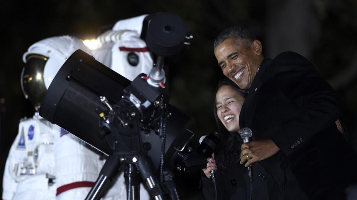 
President Barack Obama, right, shares a laugh with Agatha Sofia Alvarez-Bareiro, a high school senior from the Brooklyn borough of New York as Obama prepares to look at the moon at the second White House Astronomy Night on the South Lawn of the White House in Washington, Monday, Oct. 19, 2015. The event brings together students, teachers, astronomers, engineers, scientists, and space enthusiasts for an evening of stargazing. 
