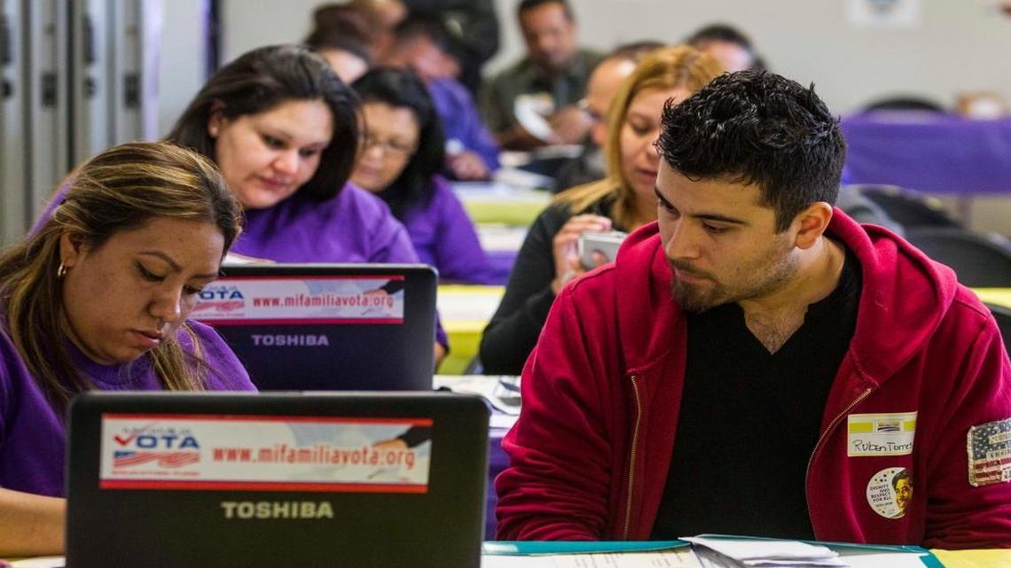 In this March 31, 2014, file photo, SEIU-UHW worker Kathy Santana, left, assists Ruben Torres, 27, during a health care enrollment event at the SEIU-UHW office in Commerce, Calif.