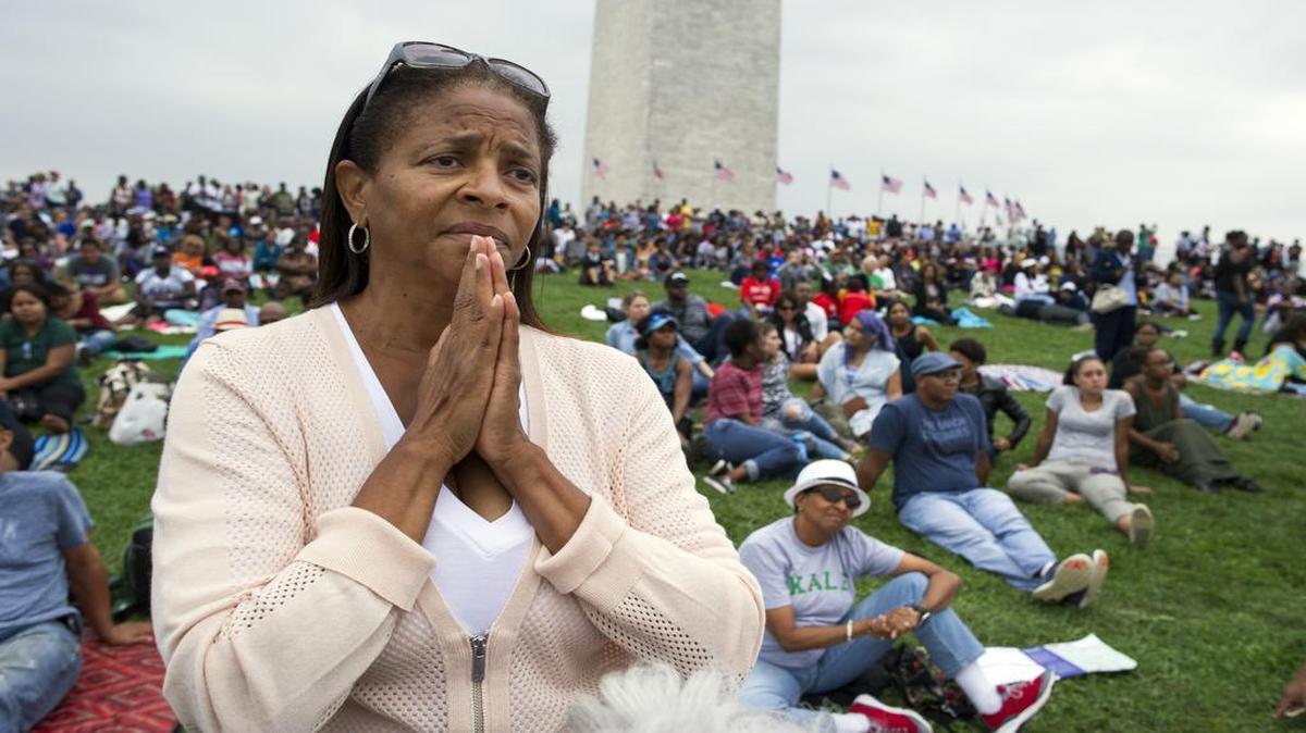 Giselle Shapiro of Los Angeles, holds her hands in prayer on the Washington Monument grounds in Washington on Saturday as she listens to President Barack Obama speak at the dedication and opening ceremony of the Smithsonian's National Museum of African American History and Culture in Washington.