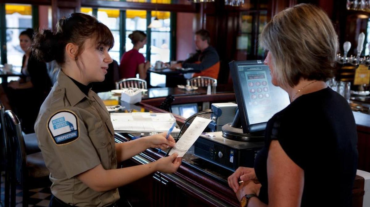 An inspector from Revenue Quebec examines a receipt at a restaurant in this undated photograph. Quebec’s tax authorities have gone further than those in the United States in combating sales tax fraud by restaurants and other businesses.