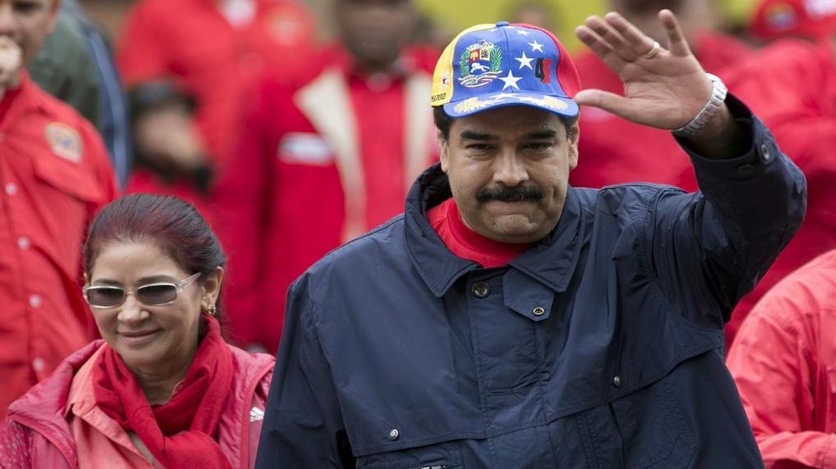 In this May 1, 2016, file photo, Venezuela's President Nicolas Maduro waves to supporters alongside first lady Cilia Flores during a labor day march in Caracas, Venezuela. Maduro frequently accuses the U.S. of working with the opposition to sow dissent where none exists.