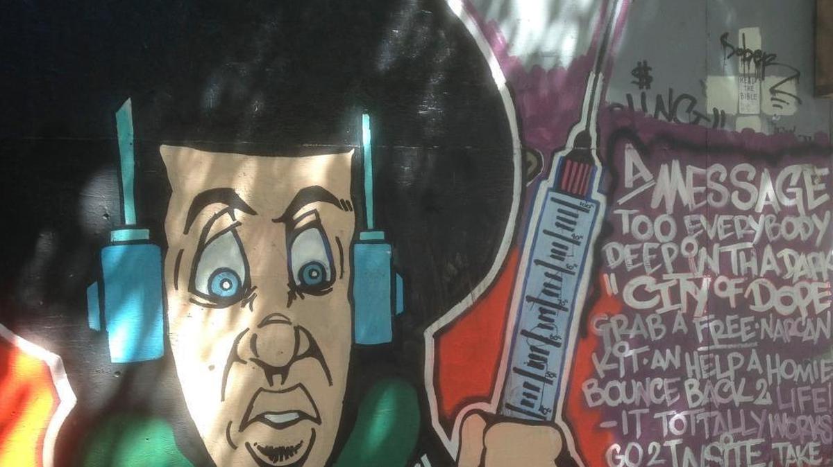 In this June 28, 2017 photo, a mural encourages people to pick up the overdose antidote Narcan at a nearby "safe injection site" on the east side of downtown Vancouver, Canada. A single safe injection site opened in 2003, run by a Vancouver nonprofit organization under authorization by Health Canada, and says it's never had an overdose death.