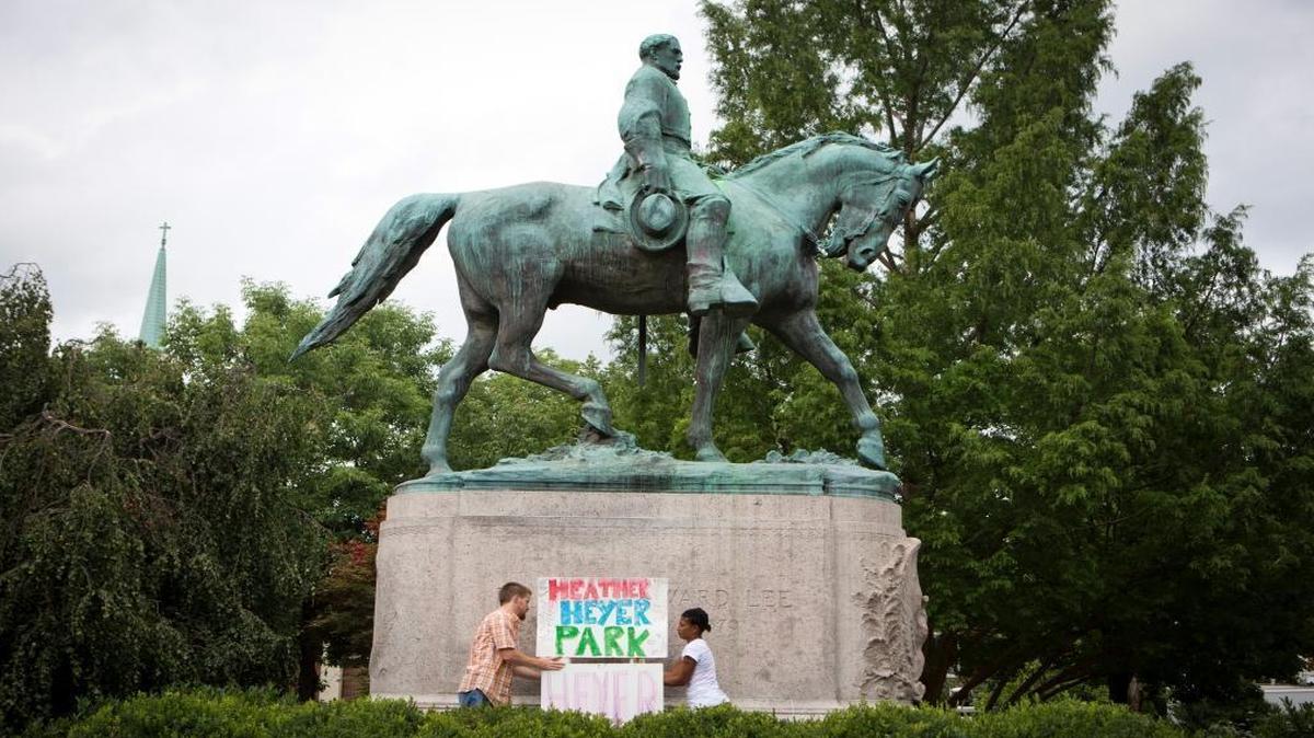 Tom Lever, 28, and Aaliyah Jones, 38, both of Charlottesville, put up a sign that says "Heather Heyer Park" at the base of the Confederate general Robert E. Lee monument in Emancipation Park Tuesday, Aug. 15 in Charlottesville, Va.