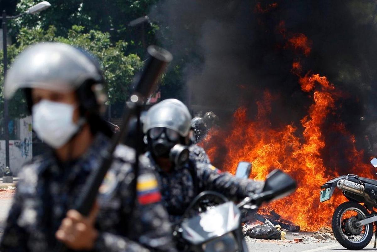 Venezuelan Bolivarian National Police move away from the flames after an explosion at Plaza Altamira during clashes against anti-government demonstrators in Caracas on Sunday.