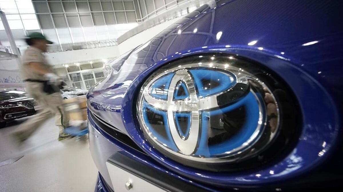 A worker walks past a Toyota car at a Toyota showroom in Tokyo on Wednesday. Toyota is recalling a total of 3.37 million vehicles.