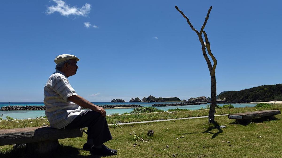 Takeichi Kakinohana, 85, lives on Aka Island where the American military landed during the Battle of Okinawa and where, eventually, the Japanese ceremonially surrendered on the beach where he sits on Aug. 1, 2015. Takeichi, conscripted by the Japanese Army at 15, hid with other islanders in the mountains for months when the Americans landed.