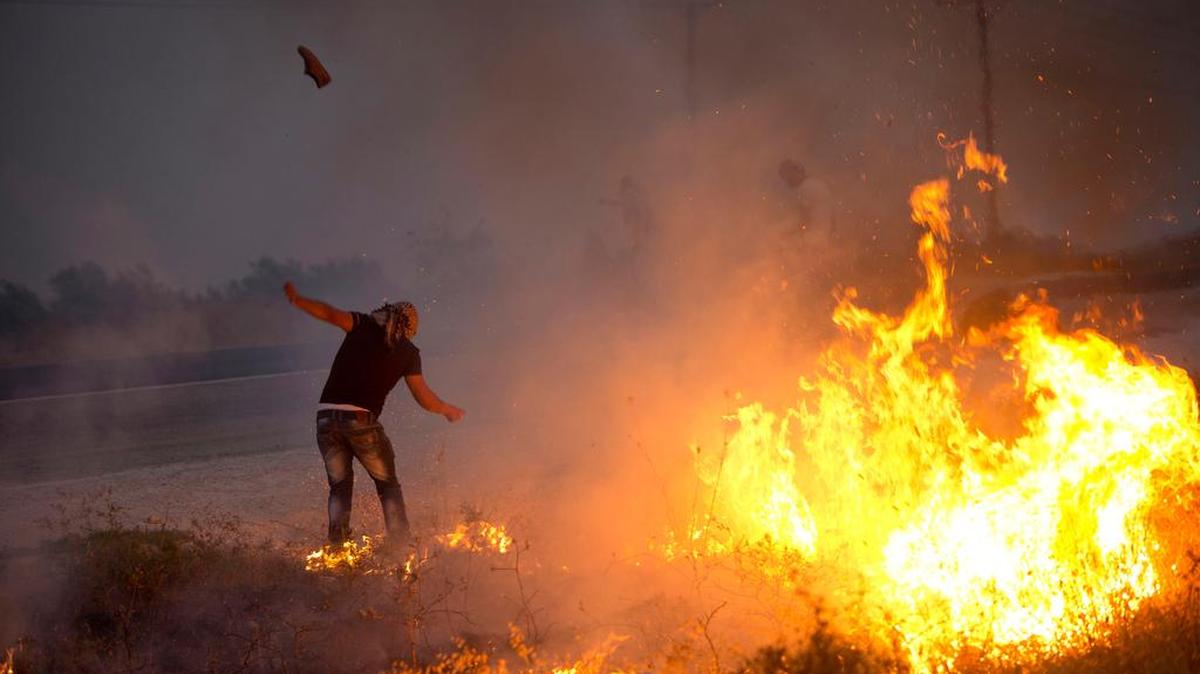 
A Palestinian demonstrator kicks a tear gas canister fired by Israeli soldiers during clashes at the West Bank town of Duma on Sunday, Aug. 2, 2015. Tensions remain high after suspected Jewish assailants set fire to a West Bank home and burned a sleeping Palestinian toddler to death. 
